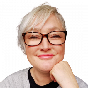 A photo of Helen who is a virtual assistant and course creator PA. She is a woman in her 40s with short white-blonde hair. She is wearing tortoiseshell style framed glasses and smiling. She has her head on her left hand.